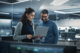 Two professionals reviewing information on a laptop in a modern office environment